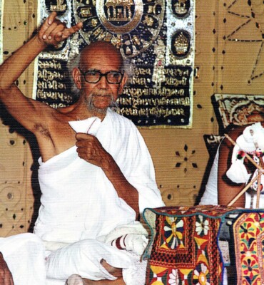 Jambuvijayji Maharaj Saheb, sits contemplatively at a table, exuding tranquility and wisdom.